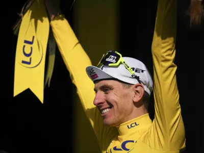 Slovenia's Tadej Pogacar, wearing the overall leader's yellow jersey, celebrates on the podium after the ninth stage of the Tour de France cycling race over 199 kilometers (123.7 miles) with start and finish in Troyes, France, Sunday, July 7, 2024. (AP Photo/Daniel Cole)