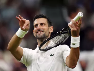 Novak Djokovic of Serbia pretends to play a violin after defeating Holger Rune of Denmark in their fourth round match at the Wimbledon tennis championships in London, Monday, July 8, 2024. (Mike Egerton/PA via AP)