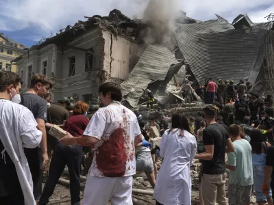 Rescuers, volunteers and medical workers, some in bloodied uniforms clean up the rubble and search victims after Russian missile hit the country's main children hospital Okhmadit, in Kyiv, Ukraine, Monday, July 8, 2024. A major Russian missile attack across Ukraine killed at least 20 people and injured more than 50 on Monday, officials said, with one missile striking a large children's hospital in the capital, Kyiv, where emergency crews searched rubble for casualties. (AP Photo/Efrem Lukatsky)