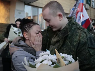 A mother of a liberated soldier reacts as she meets him after the exchange of servicemen of the Donetsk People's Republic and the Lugansk People's Republic who were imprisoned, in Amvrosiivka, Donetsk People's Republic, eastern Ukraine, Tuesday, Nov. 1, 2022. Russia and Ukraine on Saturday made an exchange of prisoners, which took place according to the formula "50 to 50". (AP Photo/Alexei Alexandrov)