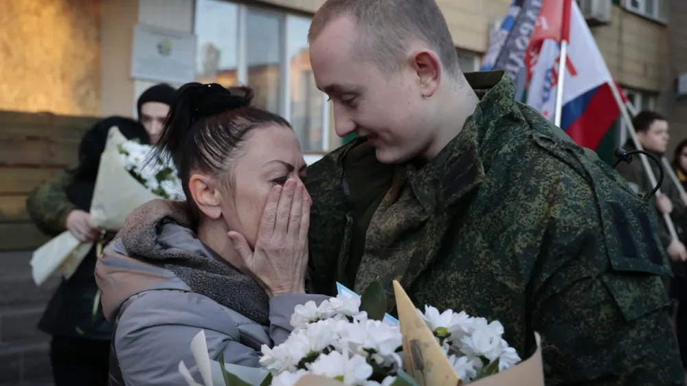 A mother of a liberated soldier reacts as she meets him after the exchange of servicemen of the Donetsk People's Republic and the Lugansk People's Republic who were imprisoned, in Amvrosiivka, Donetsk People's Republic, eastern Ukraine, Tuesday, Nov. 1, 2022. Russia and Ukraine on Saturday made an exchange of prisoners, which took place according to the formula "50 to 50". (AP Photo/Alexei Alexandrov)