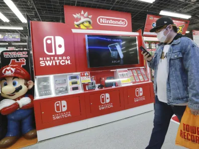 A man walks an advertisement of Nintendo Switch at an electronics retail chain store in Tokyo on Oct. 13, 2021. Japanese video game maker Nintendo recorded a 34% surge in fiscal first half profits Tuesday, Nov. 8, 2022, as products for its Switch console like "Splatoon 3," a paint-shooting game, sold well. (AP Photo/Koji Sasahara)