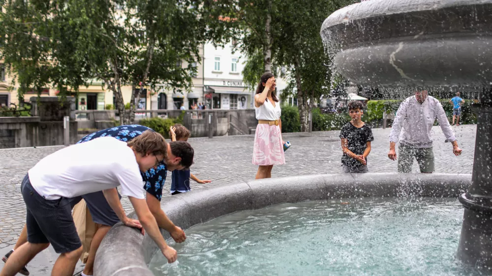 - Mimoidoči v Ljubljani se skušajo ohladiti v vodnjaku na Novem trgu.- 10.07.2024. - Vročinski val je zajelSlovenijo s temperaturima preko 30 stopinj.//FOTO: Bojan Velikonja