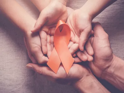 Adult and child hands holding orange Ribbons, Leukemia cancer and Multiple sclerosis, COPD and ADHD awareness, world kidney day