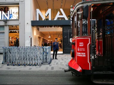 A tram passes the Istiklal Avenue, a popular spot for shoppers and tourists, as a blast site is seen behind a police barricade in Istanbul, Turkey, November 14, 2022. REUTERS/Dilara Senkaya