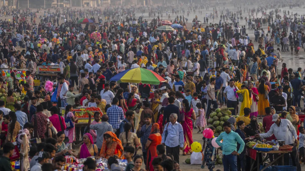 People crowd at the Juhu beach on the Arabian Sea coast in Mumbai, India, Sunday, Nov. 13, 2022. The 8 billionth baby on Earth is about to be born on a planet that is getting hotter. But experts in climate science and population both say the two issues aren't quite as connected as they seem. (AP Photo/Rafiq Maqbool)