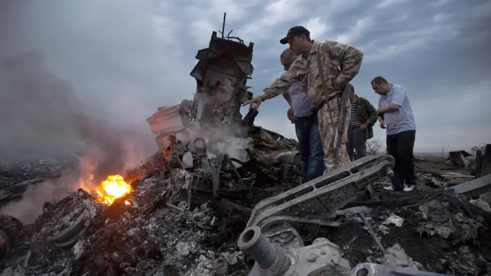 FILE - People inspect the crash site of a passenger plane near the village of Grabovo, Ukraine, on July 17, 2014. A Dutch court on Thursday is set to deliver verdicts in the long-running trial of three Russians and a Ukrainian rebel for their alleged roles in the shooting down of Malaysia Airlines flight MH17 over conflict-torn eastern Ukraine. (AP Photo/Dmitry Lovetsky, File)