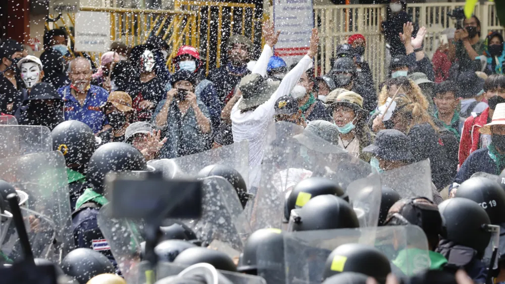 Protesters throw fermented fish sauce to riot police during a protest against the Asia-Pacific Economic Cooperation (APEC) forum, Friday, Nov. 18, 2022, in Bangkok Thailand. (AP Photo/Sarot Meksophawannakul)