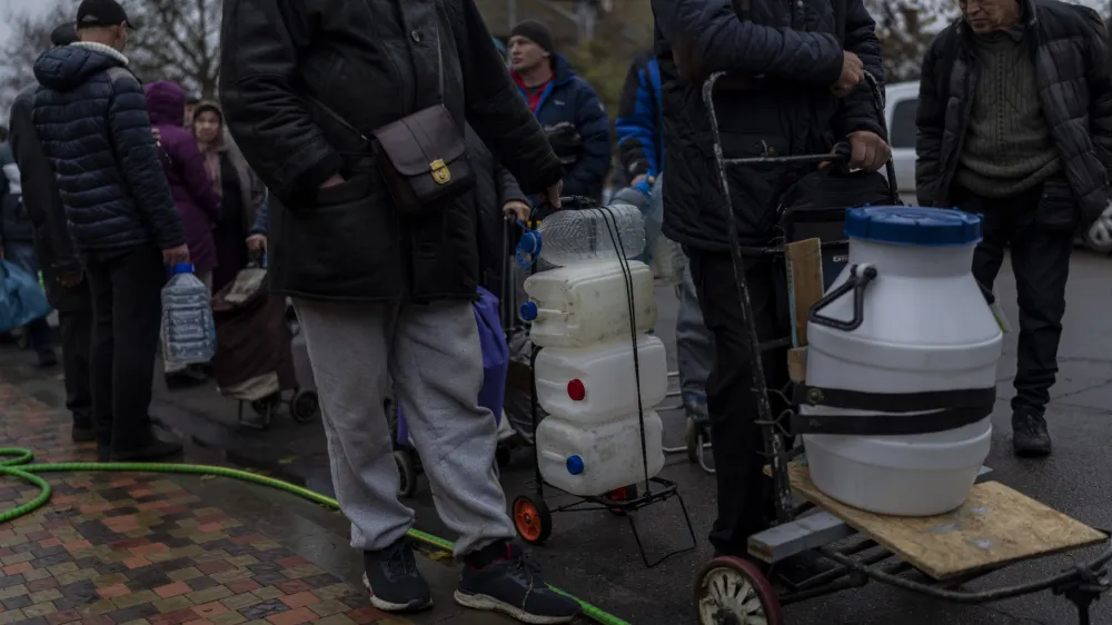 Residents queue to fill containers with drinking water in Kherson, southern Ukraine, Sunday, Nov. 20, 2022. Russian forces fired tank shells, rockets and other artillery on the city of Kherson, which was recently liberated from Ukrainian forces. (AP Photo/Bernat Armangue)