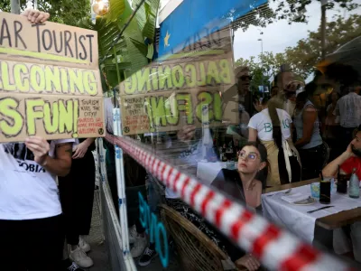 A tourist watches as demonstrators protest against mass tourism in Barcelona, Spain, July 6, 2024. The Catalan capital received more than 12 million tourists in 2023 and expects more in 2024. REUTERS/Bruna Casas / Foto: Bruna Casas