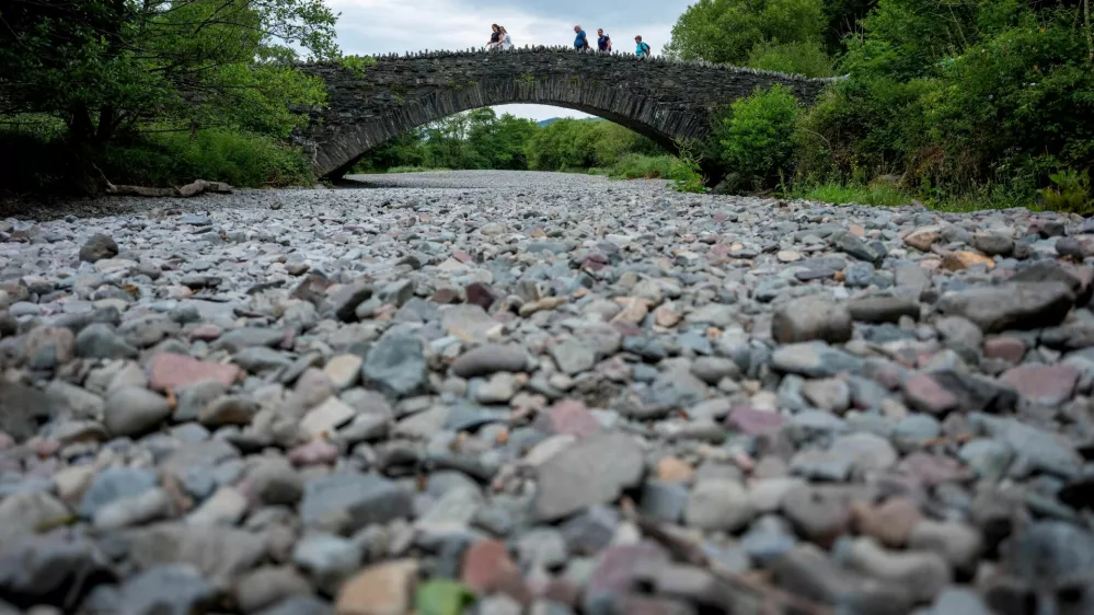 People cross a bridge over the dry river bed of the River Derwent after a prolonged period of dry weather in Grange, Britain, June 18, 2023. REUTERS/Phil Noble   TPX IMAGES OF THE DAY