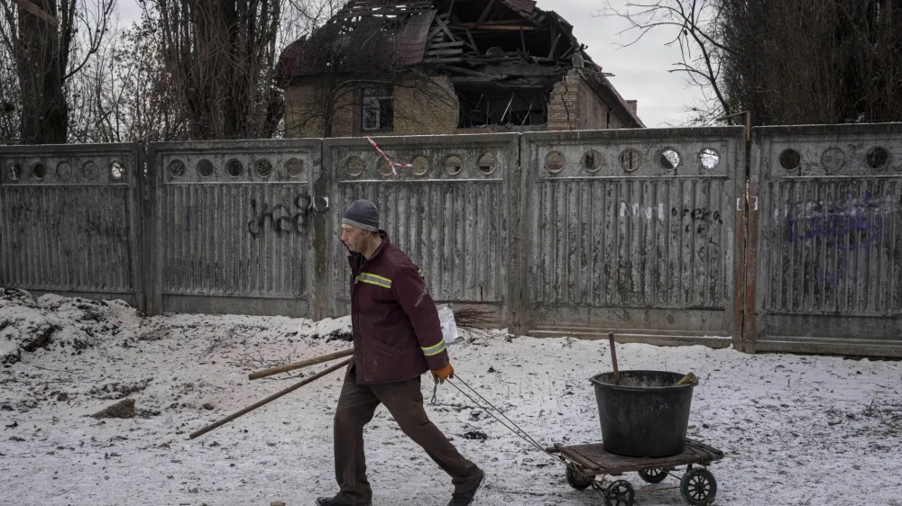 A municipal worker walks in front of a tax office building that have been heavily damaged by a Russian attack in Kyiv, Ukraine, Wednesday, Dec. 14, 2022. (AP Photo/Evgeniy Maloletka)