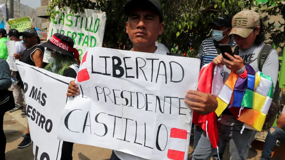 A man holds a placard that reads: "Freedom for President Castillo" as supporters of ousted Peruvian leader Pedro Castillo gather outside the police prison where he is detained, in Lima, December 14, 2022. REUTERS/Sebastian Castaneda