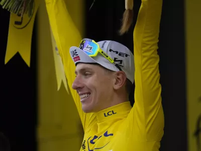 Stage winner Slovenia's Tadej Pogacar, wearing the overall leader's yellow jersey, celebrates on the podium after the fourteenth stage of the Tour de France cycling race over 151.9 kilometers (94.4 miles) with start in Pau and finish in Saint-Lary-Soulan Pla d'Adet, France, Saturday, July 13, 2024. (AP Photo/Jerome Delay)