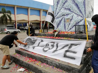 Arema football club supporters, known as Aremania, put a banner on a monument outside the Kanjuruhan stadium to pay condolence to the victims, after a riot and stampede following soccer match between Arema vs Persebaya outside in Malang, East Java province, Indonesia, October 2, 2022. REUTERS/Willy Kurniawan