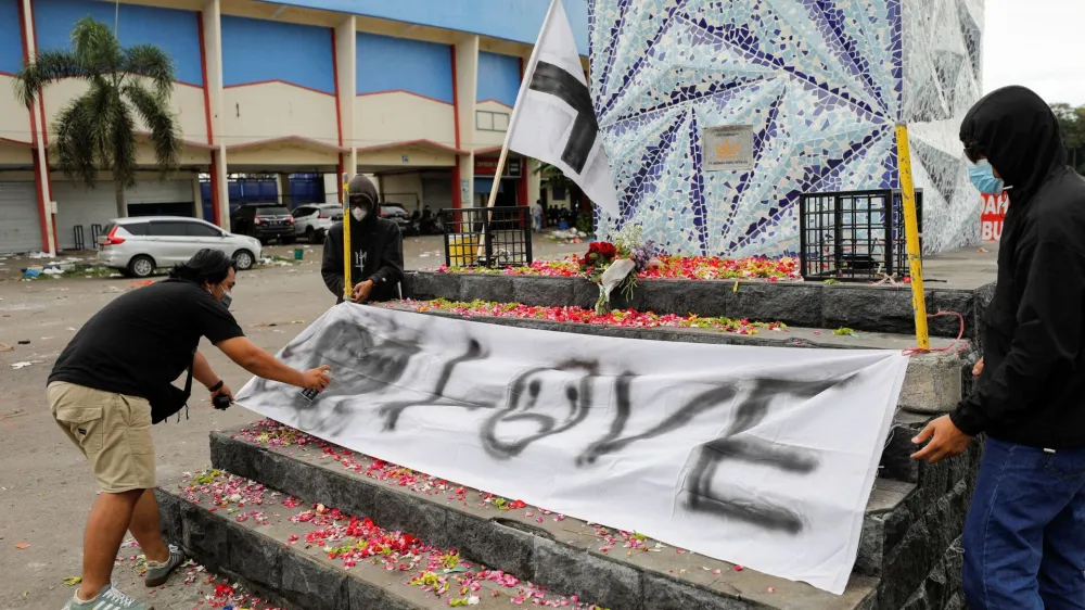 Arema football club supporters, known as Aremania, put a banner on a monument outside the Kanjuruhan stadium to pay condolence to the victims, after a riot and stampede following soccer match between Arema vs Persebaya outside in Malang, East Java province, Indonesia, October 2, 2022. REUTERS/Willy Kurniawan