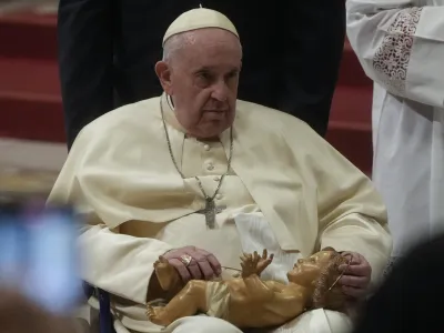 Pope Francis holds a statue of Baby Jesus as he presides over Christmas Eve Mass, at St. Peter's Basilica at the Vatican, Saturday Dec. 24, 2022. (AP Photo/Gregorio Borgia)