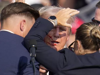 Republican presidential candidate former President Donald Trump is helped off the stage by U.S. Secret Service agents at a campaign event in Butler, Pa., on Saturday, July 13, 2024. (AP Photo/Gene J. Puskar)