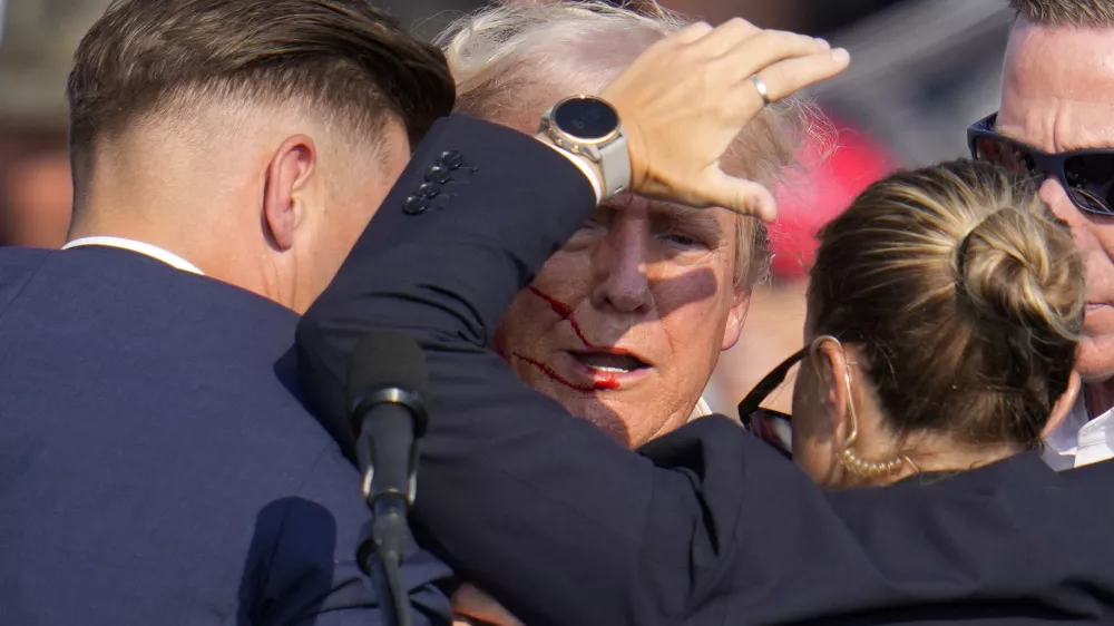 Republican presidential candidate former President Donald Trump is helped off the stage by U.S. Secret Service agents at a campaign event in Butler, Pa., on Saturday, July 13, 2024. (AP Photo/Gene J. Puskar)