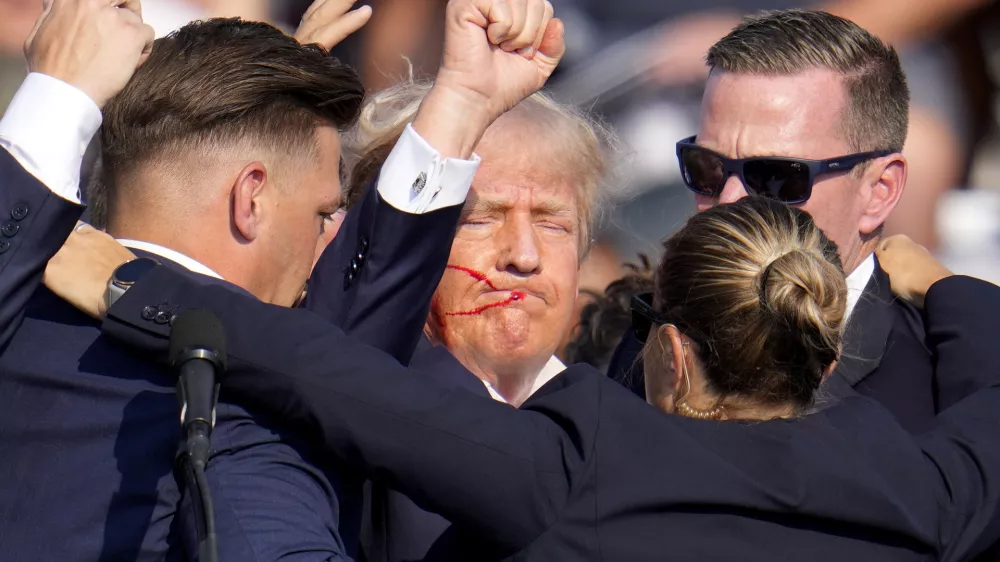 Republican presidential candidate former President Donald Trump is helped off the stage by U.S. Secret Service agents at a campaign event in Butler, Pa., on Saturday, July 13, 2024. (AP Photo/Gene J. Puskar)