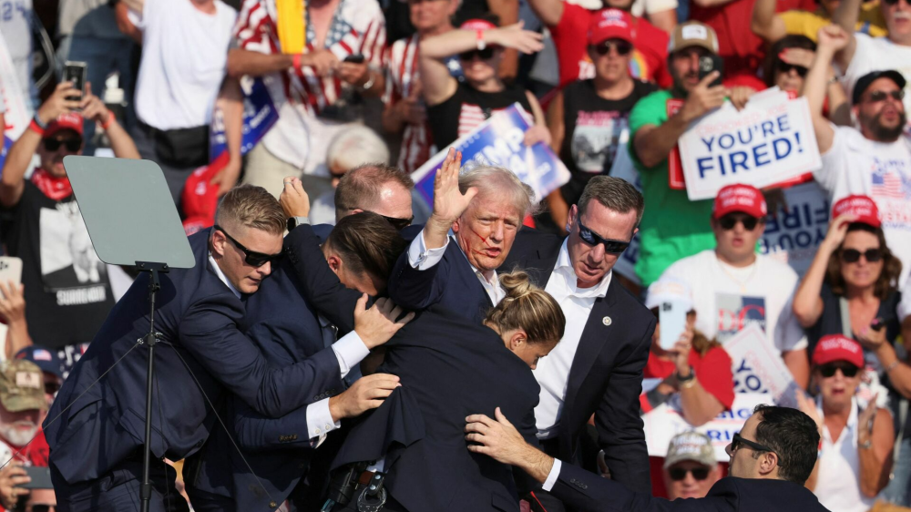 Republican presidential candidate and former U.S. President Donald Trump gestures with a bloodied face while he is assisted by U.S. Secret Service personnel after he was shot in the right ear during a campaign rally at the Butler Farm Show in Butler, Pennsylvania, U.S., July 13, 2024. REUTERS/Brendan McDermid