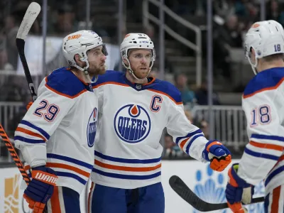 Edmonton Oilers center Connor McDavid, middle, celebrates with center Leon Draisaitl, left, and left wing Zach Hyman after scoring against the San Jose Sharks during the second period of an NHL hockey game in San Jose, Calif., Friday, Jan. 13, 2023. (AP Photo/Godofredo A. Vásquez)