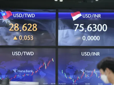 A currency trader stands near screens showing the foreign exchange rates at a foreign exchange dealing room in Seoul, South Korea, Wednesday, March 30, 2022. Asian stock markets followed Wall Street higher on Wednesday as talks on ending Russia's war on Ukraine appeared to make progress. (AP Photo/Lee Jin-man)