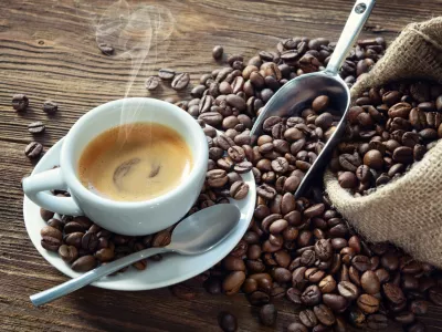 ﻿Cup of espresso with coffee beans, bag, scoop and steam on rustic wooden background