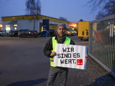 20 January 2023, Berlin: The shop steward Ahmet Almaz from the parcel delivery Reinickendorf holds a placard during a nationwide postal strike. In the collective bargaining dispute at Deutsche Post, the Verdi union had called for nationwide strikes. Photo: Joerg Carstensen/dpa