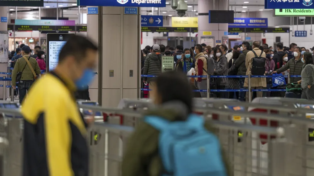 FILE - Travelers wearing face masks line up at the immigration counters of the departure hall at Lok Ma Chau station following the reopening of crossing border with mainland China, in Hong Kong, Sunday, Jan. 8, 2023. Hong Kong authorities announced Friday, Feb. 3, 2023, that they will lift a quota on the number of cross-border travelers with China and scrap mandatory COVID-19 PCR testing requirements as both places seek to drive economic growth. (AP Photo/Bertha Wang, File)