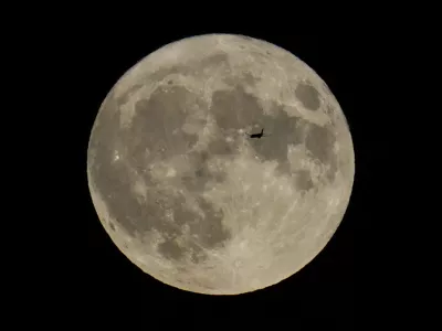 FILE - A plane passes in front of the moon, Aug. 30, 2023, in Chicago. Scientists have confirmed a cave on the moon, not far from where Neil Armstrong and Buzz Aldrin landed 55 years ago this week, and suspect there are hundreds more that could house future astronauts. (AP Photo/Kiichiro Sato, file)