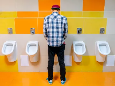 young man in the public toilet, standing next to the urinal in the trade center / Foto: Михаил Руденко