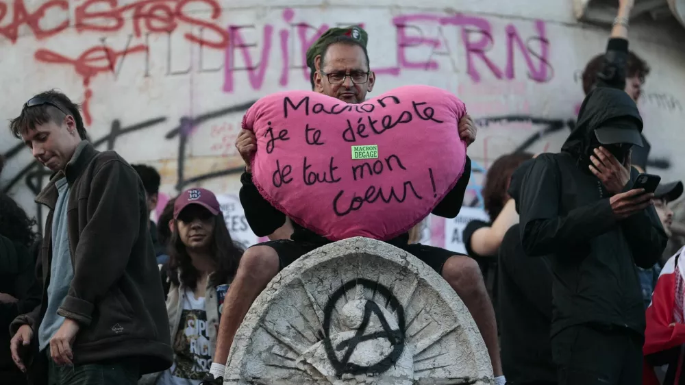 A protester holds a big plush heart with the slogan "Macron, I hate you with all my heart" as people gather at the Place de la Republique after partial results in the second round of the early French parliamentary elections, in Paris, France, July 7, 2024. REUTERS/Abdul Saboor