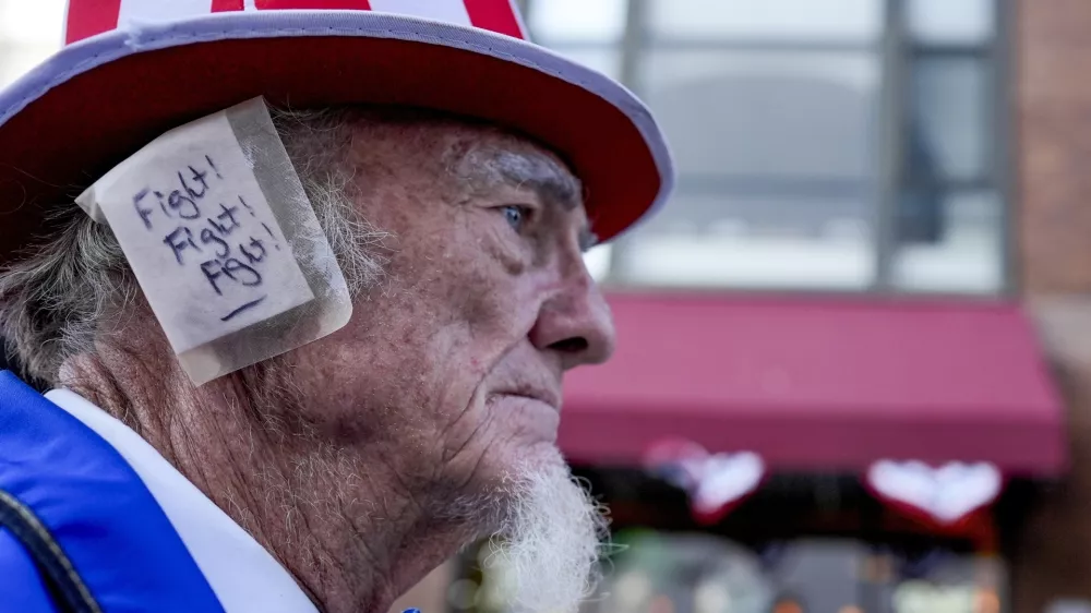 A supporter, donning an ear bandage in solidarity with former President Donald Trump after an assassination attempt, makes his way to the Republican National Convention in Milwaukee, July 18, 2024. (AP Photo/Mike Stewart)