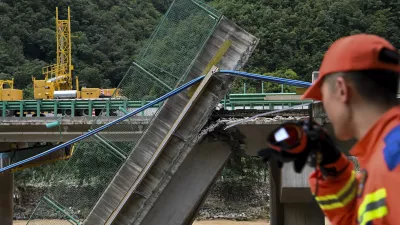 In this photo released by Xinhua News Agency, a rescuer looks at the collapsed bridge as they conduct a search and rescue on a river in Zhashui County in Shangluo City, northwest China's Shaanxi Province, Saturday, July 20, 2024. Chinese authorities say several people have died and more than dozen are missing in the partial collapse of a highway bridge in the northwest of the country following heavy storms and flooding. A similar number are missing in the southwest after dozens of houses were destroyed by storms. (Zou Jingyi/Xinhua via AP)