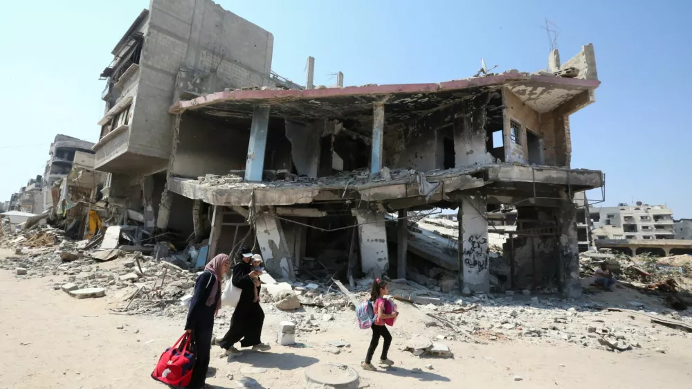 A Palestinian woman holds a child as they flee the eastern part of Khan Younis to make their way after they were ordered by Israeli army to evacuate their neighborhoods, amid Israel-Hamas conflict, in Khan Younis in the southern Gaza Strip July 22, 2024. REUTERS/Hatem Khaled