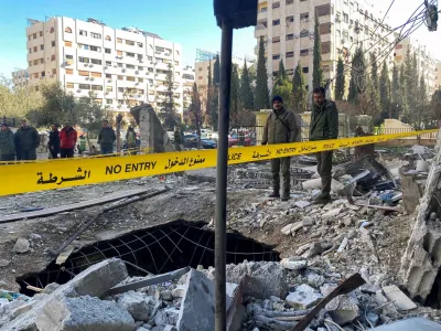 Police officers stand on the rubble of a damaged building at the site of a rocket attack, in central Damascus' Kafr Sousa neighborhood, Syria, February 19, 2023. REUTERS/Firas Makdessi