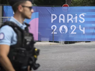 FILE - A police officer walks past a Paris Olympics canvas at the 2024 Summer Olympics, Saturday, July 20, 2024, in Paris, France. Three days before the start of the Olympics, France's Interior Minister has hailed the country's law enforcement for their hard work in making the Paris Games safe for 10,500 athletes and millions of visitors. (AP Photo/Thomas Padilla, File)