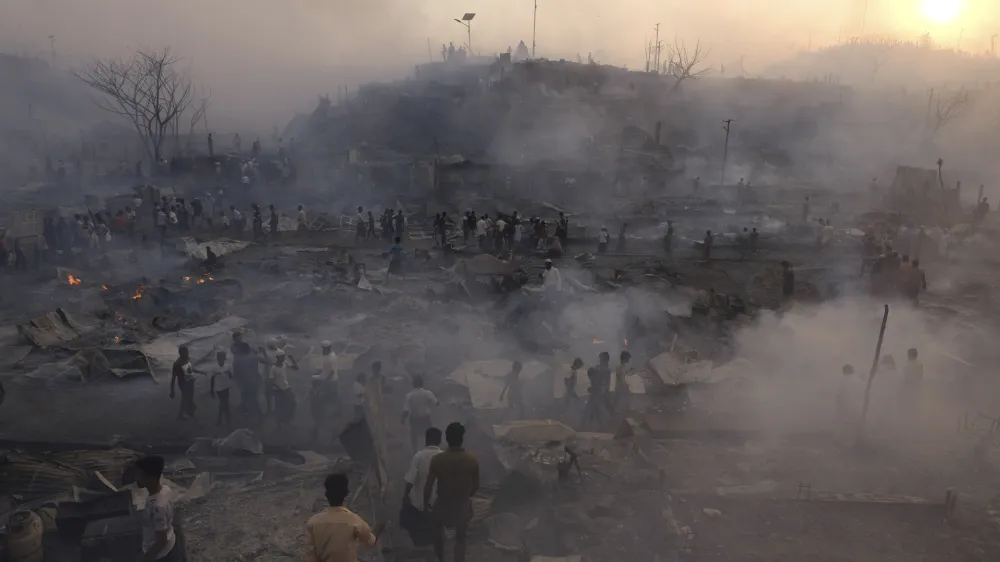 Rohingya refugees try to salvage their belongings after a major fire in their Balukhali camp at Ukhiya in Cox's Bazar district, Bangladesh, Sunday, March 5, 2023. A massive fire raced through a crammed camp of Rohingya refugees in southern Bangladesh on Sunday, leaving thousands homeless, a fire official and the United Nations said. (AP Photo/Mahmud Hossain Opu)