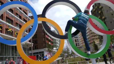 Regis Scott, a polyclinic medical team member, climbs the Olympic rings for a photo, in the Olympic Village at the 2024 Summer Olympics, Tuesday, July 23, 2024, in Paris, France. (AP Photo/Rebecca Blackwell)