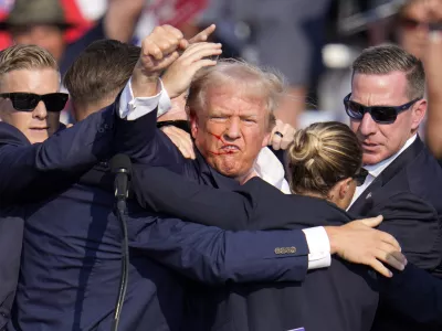 Republican presidential candidate former President Donald Trump pumps his fist as he is helped off the stage at a campaign event in Butler, Pa., on Saturday, July 13, 2024. (AP Photo/Gene J. Puskar)