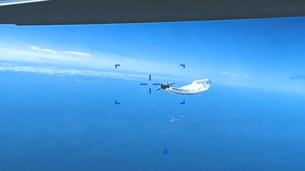 A Russian Su-27 aircraft dumps fuel while flying upon a U.S. Air Force intelligence, surveillance, and reconnaissance unmanned MQ-9 aircraft over the Black Sea, March 14, 2023 in this still image taken from a handout video. Courtesy of U.S. European Command/Handout via REUTERS  THIS IMAGE HAS BEEN SUPPLIED BY A THIRD PARTY. MANDATORY CREDIT.