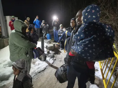 A family of asylum-seekers cross the border just after the midnight deadline at Roxham Road from New York into Canada, early Saturday, March 25, 2023, in Champlain, N.Y. The irregular border crossing is now permanently closed. (Ryan Remiorz/The Canadian Press via AP)