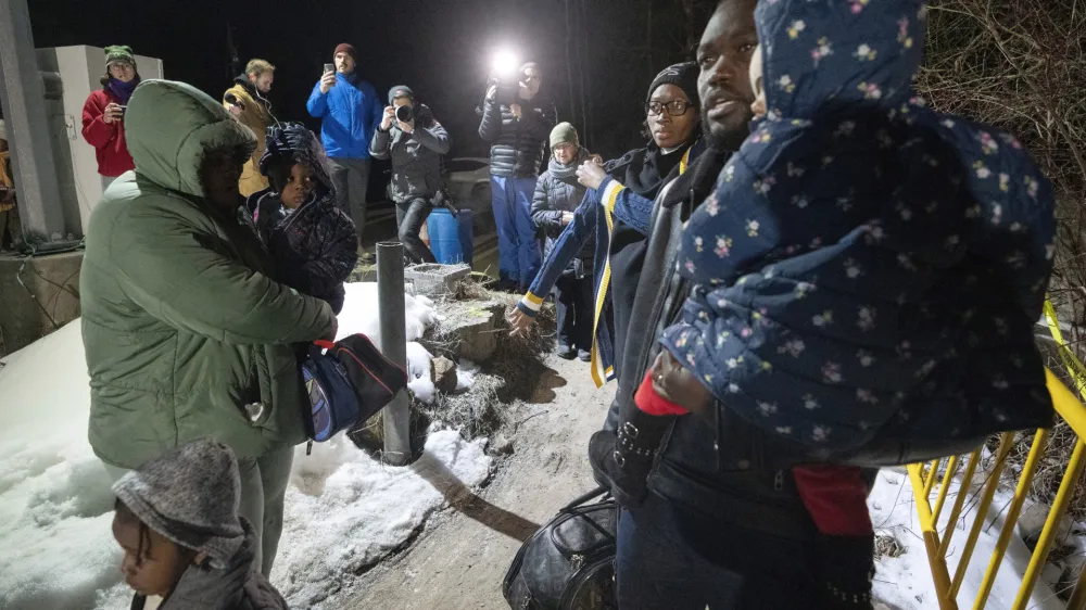 A family of asylum-seekers cross the border just after the midnight deadline at Roxham Road from New York into Canada, early Saturday, March 25, 2023, in Champlain, N.Y. The irregular border crossing is now permanently closed. (Ryan Remiorz/The Canadian Press via AP)