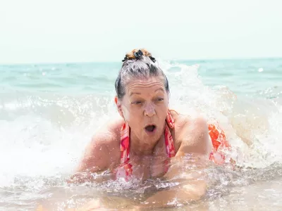 senior adult woman having fun with the waves of the sea on the shore of a beach on summer vacation during a heat wave / Foto: David Petrus Ibars