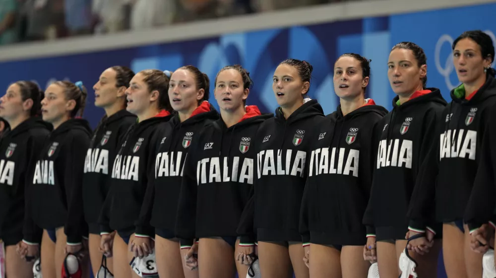 Players from Italy listen to their national anthem prior to a women's water polo group B preliminary match between Italy and USA, at the 2024 Summer Olympics, Wednesday, July 31, 2024, in Saint-Denis, France. (AP Photo/Luca Bruno)