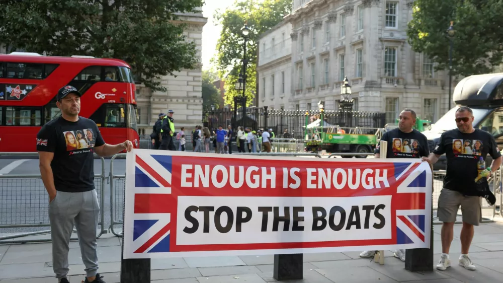 People hold a banner on the day of a protest against illegal immigration outside of Downing Street in London Britain, July 31, 2024. REUTERS/Hollie Adams