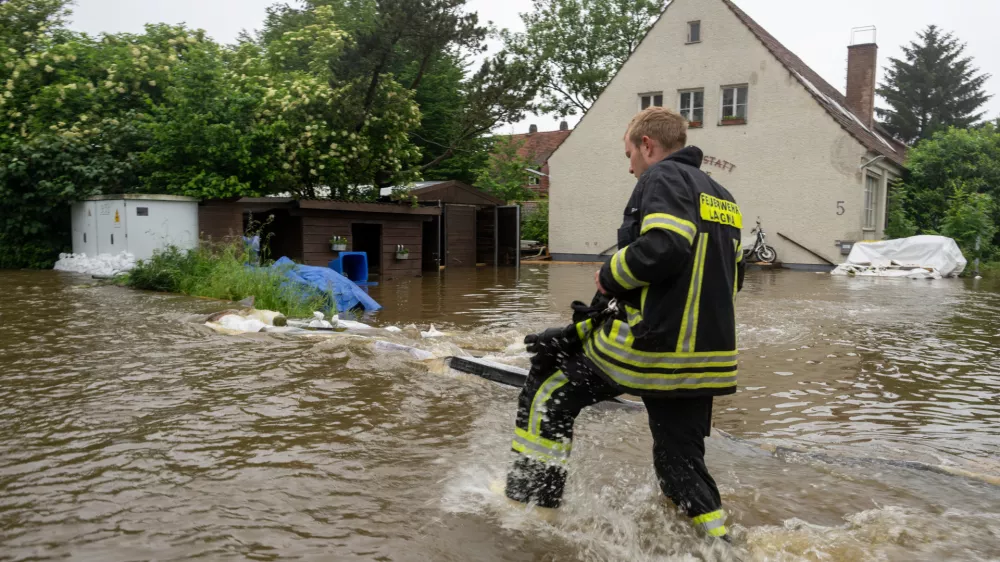 02 June 2024, Bavaria, Wertingen: A firefighter walks across a flooded street. After the heavy rainfall of the last few days, there was severe flooding in the region. Photo: Stefan Puchner/dpa