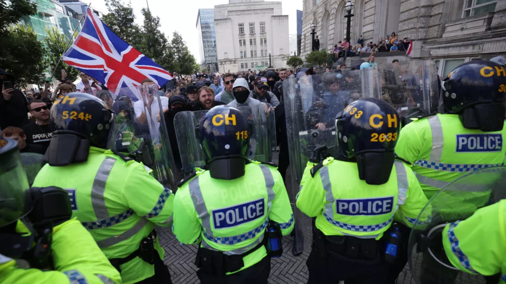 03 August 2024, United Kingdom, Liverpool: Police officers face protesters, following the stabbing attacks on Monday in Southport, which three young children were killed. Photo: James Speakman/PA Wire/dpa