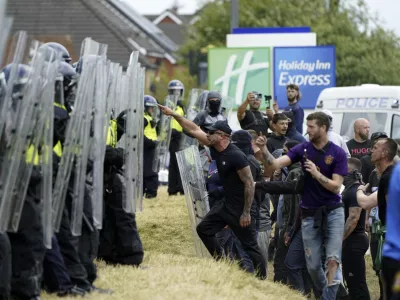 Demonstrators face police officers as trouble flares during an anti-immigration protest outside the Holiday Inn Express in Rotherham, England, Sunday Aug. 4, 2024. (Danny Lawson/PA via AP)